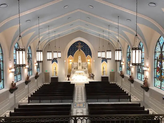 A beautifully adorned church interior with dark wooden pews and ornate stained glass windows featuring custom lighting by crenshaw