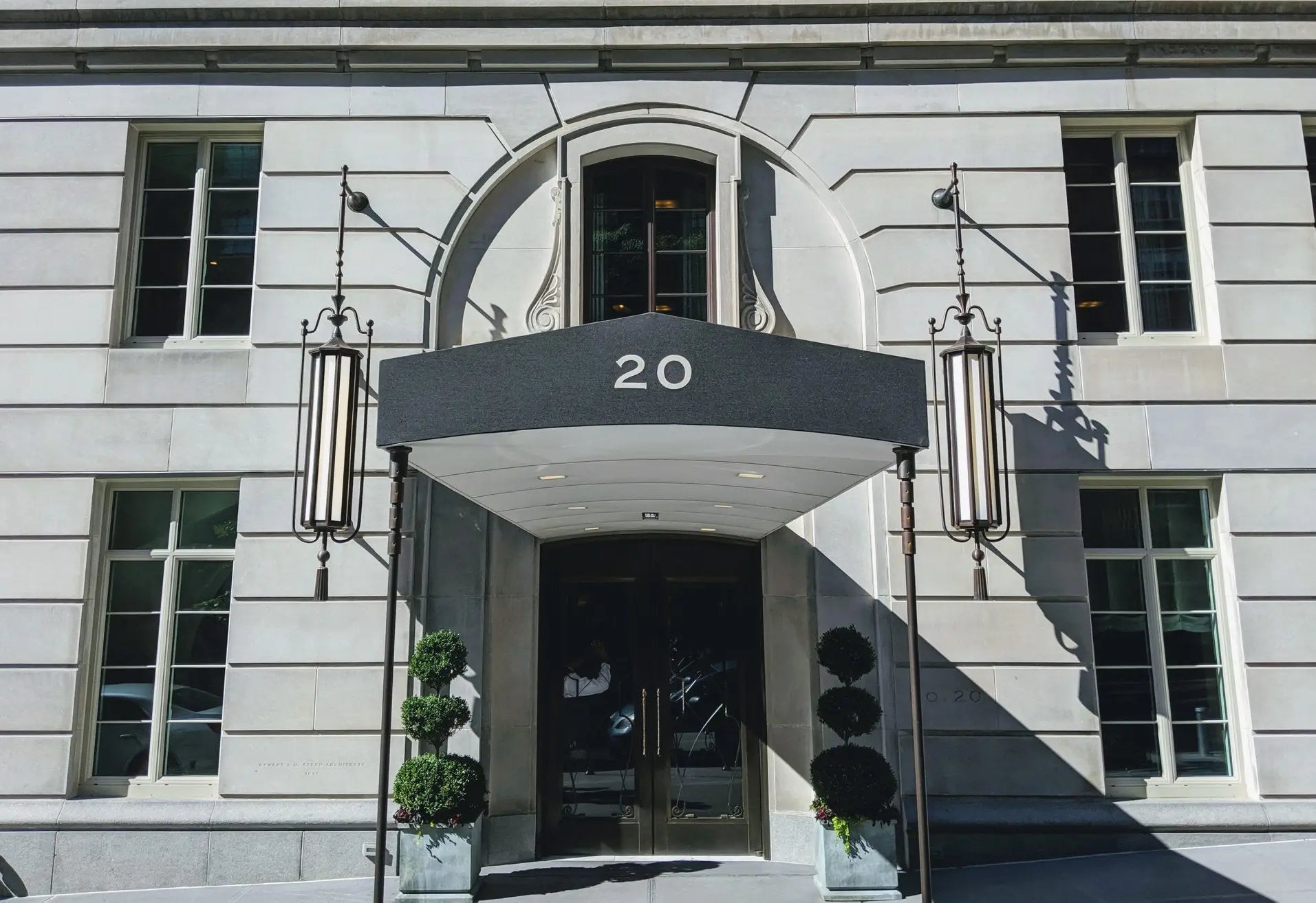 Elegant stone building facade in new york featuring a modern awning and decorative lanterns at crenshaw lights 20 east end