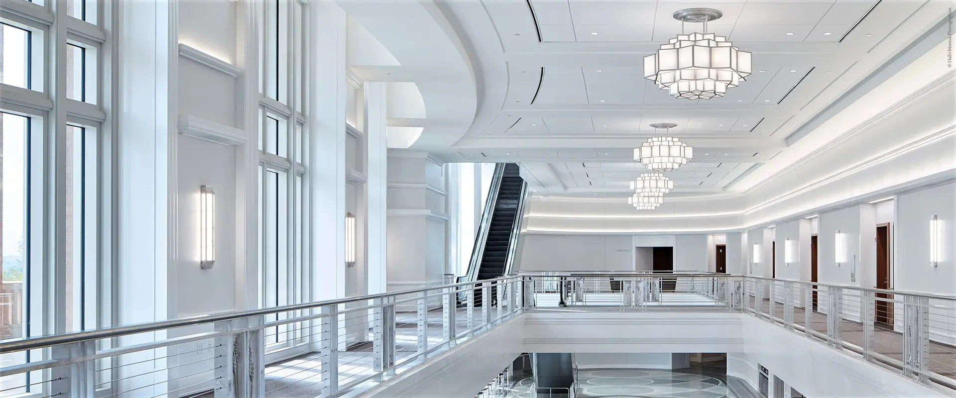 A modern multi-level interior space at dickies arena featuring an escalator chandeliers and large windows