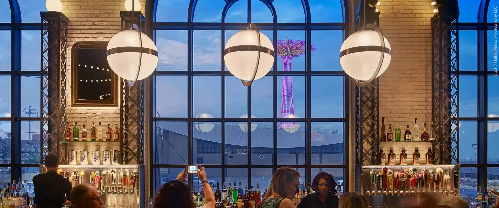 A bar with a wide selection of beverages and a view of the city.