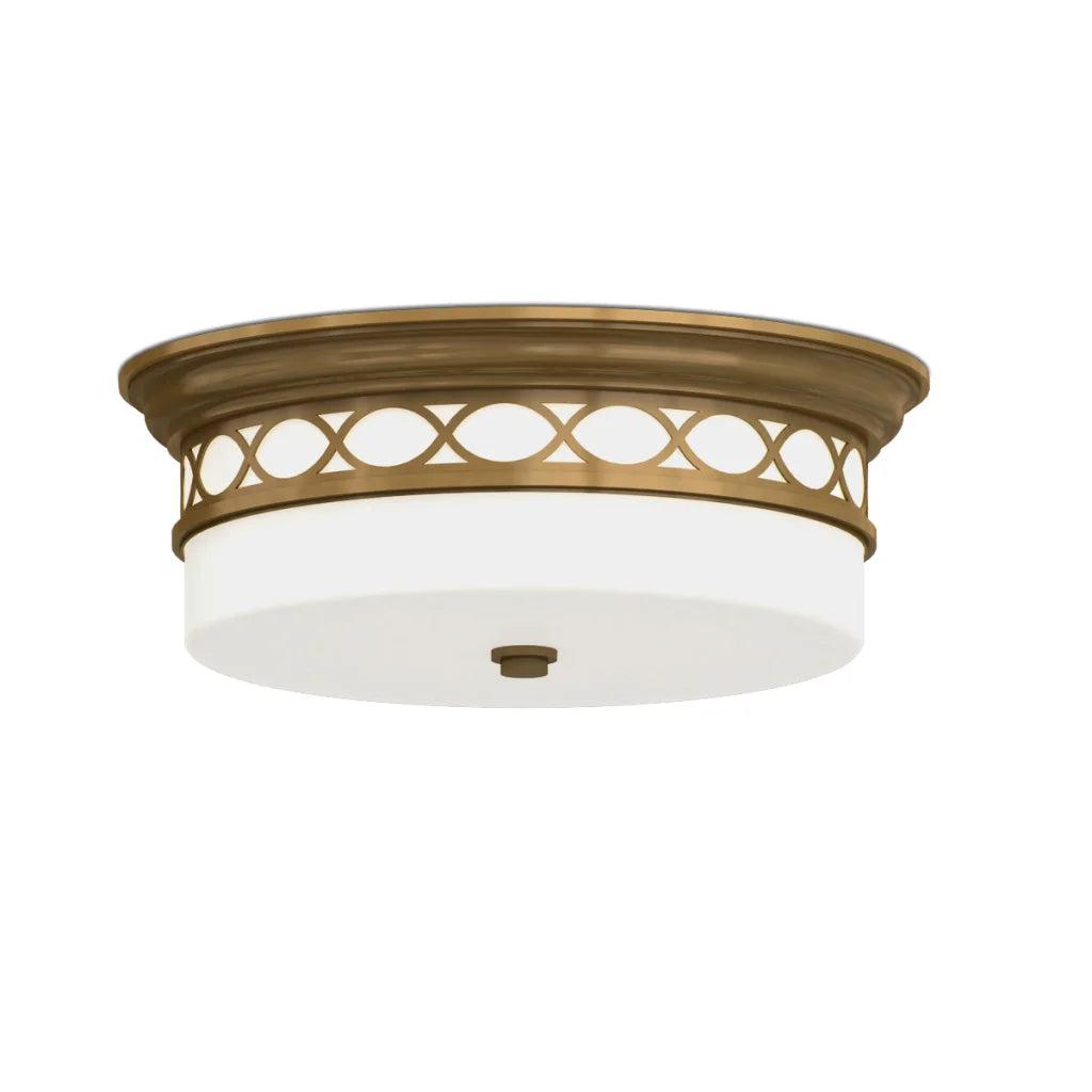 Antique brass flush mount ceiling light with white glass shade and decorative cut-out pattern.