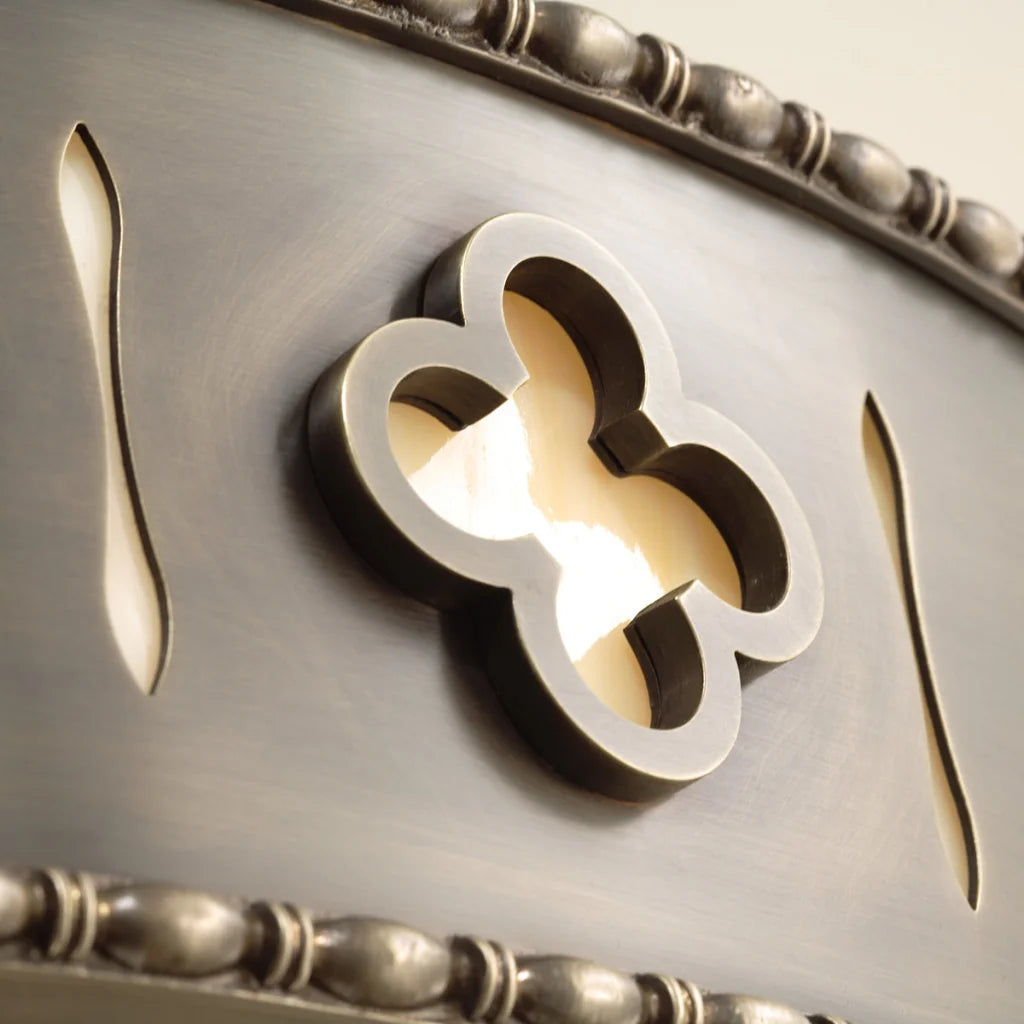 Silver clover-shaped wall sconce with a warm glow.