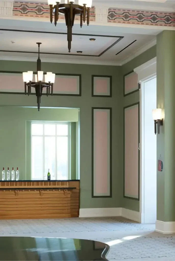 A modern elegant room featuring two palladium chandeliers with crystal details against soft green walls and a bar