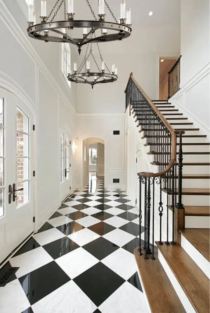 A Skellig chandelier in dark metal hangs in a grand entryway with black and white checkered marble flooring