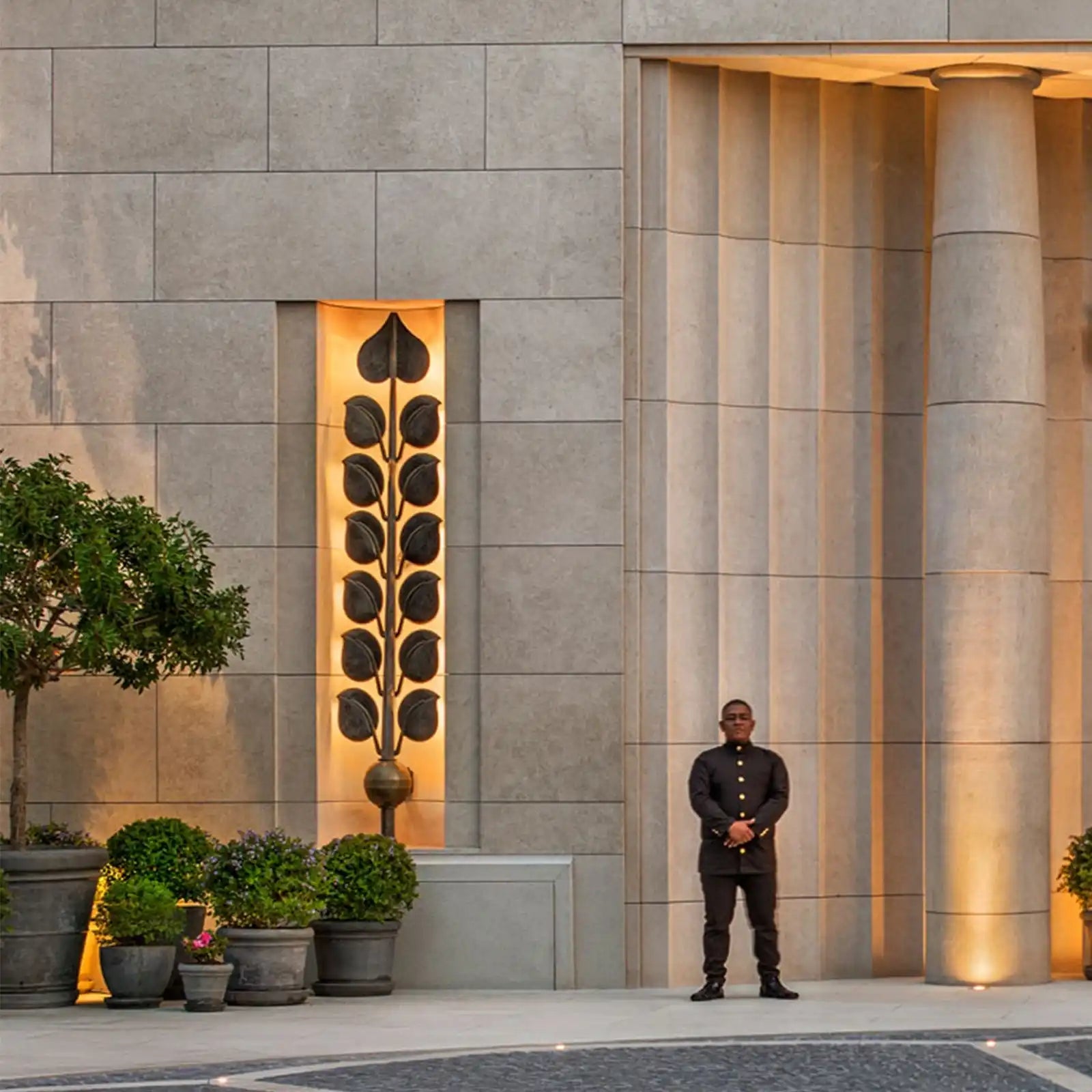 An elegantly uniformed doorman standing in front of a modern building entrance.