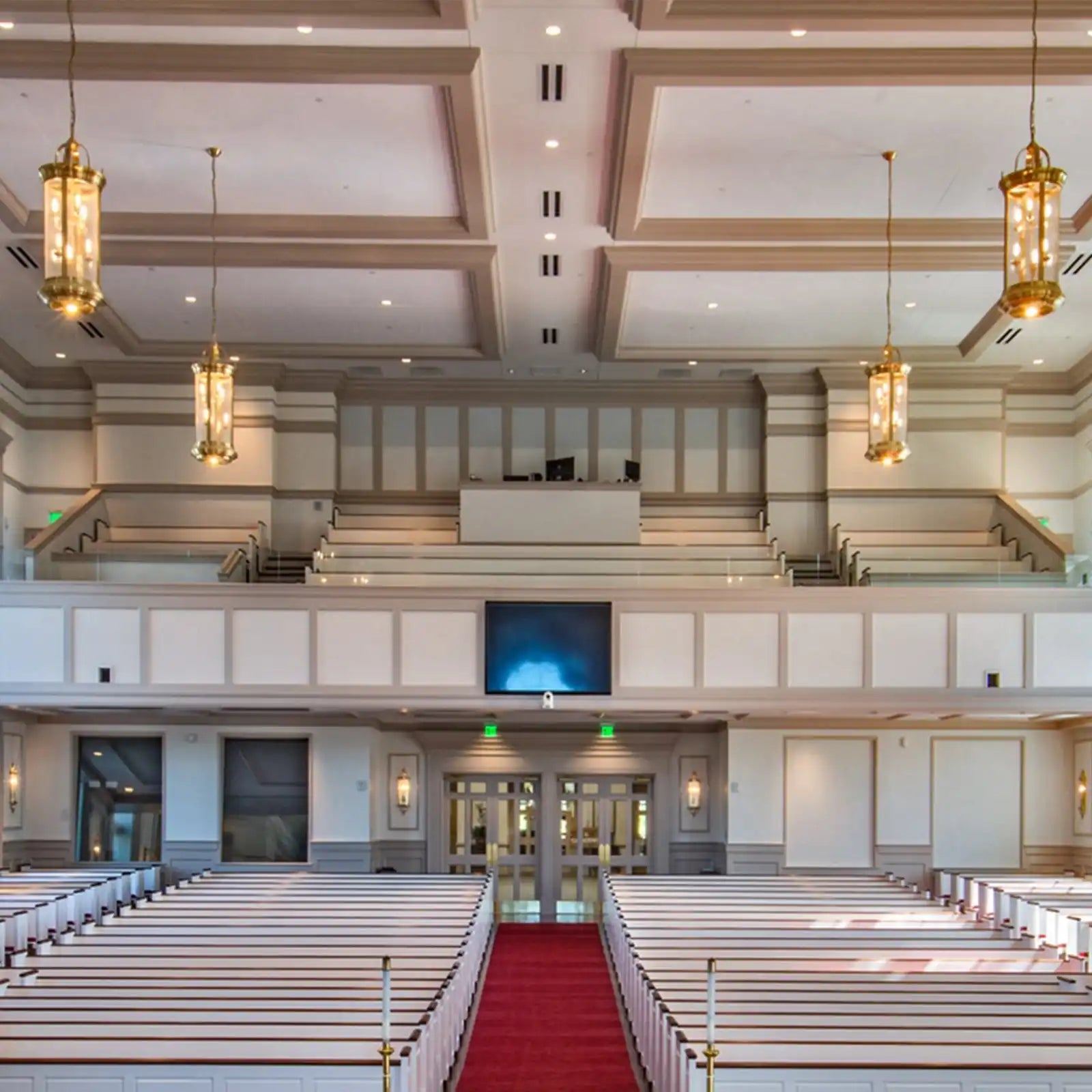 A large, empty church sanctuary with rows of white pews and a red carpeted aisle.