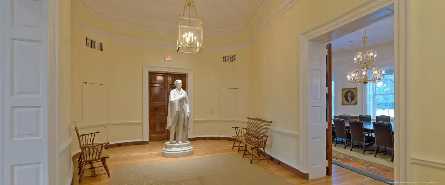 A white marble statue of a standing man in formal attire.
