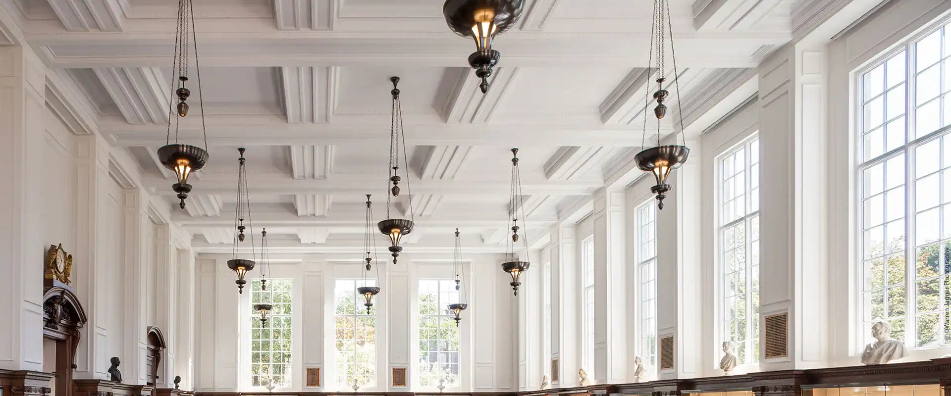 A grand hall with tall windows and ornate hanging light fixtures.