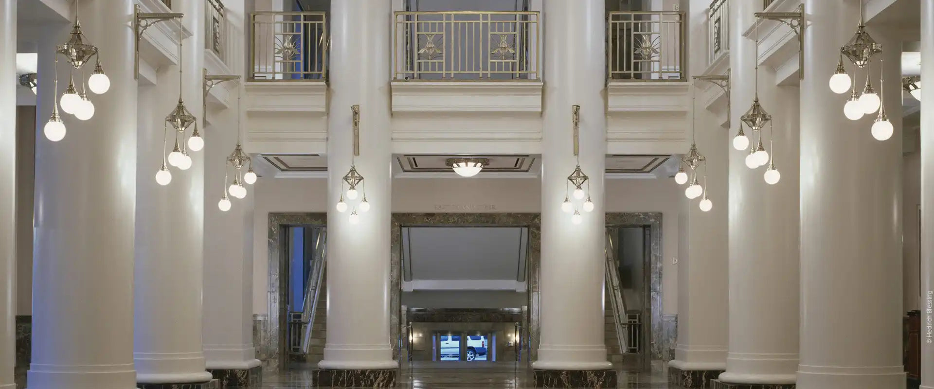 Grand interior hallway with ornate lighting and columns.