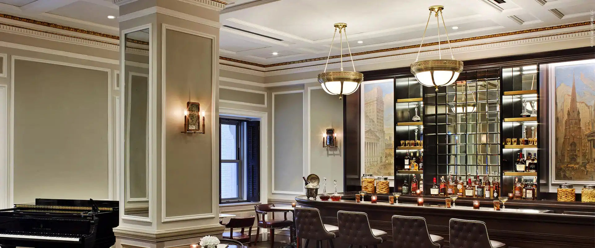 A luxurious bar area with a long counter, multiple bar stools, and various bottles of alcohol displayed on shelves.