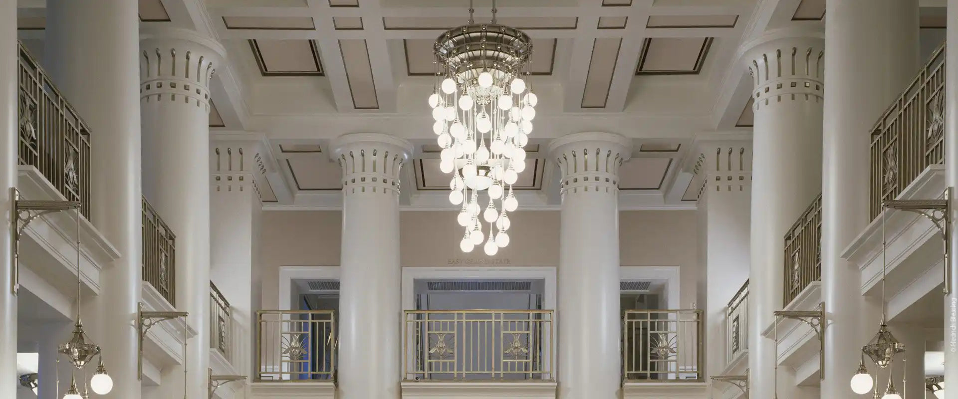 A multi-tiered modern chandelier with numerous glowing spherical bulbs.