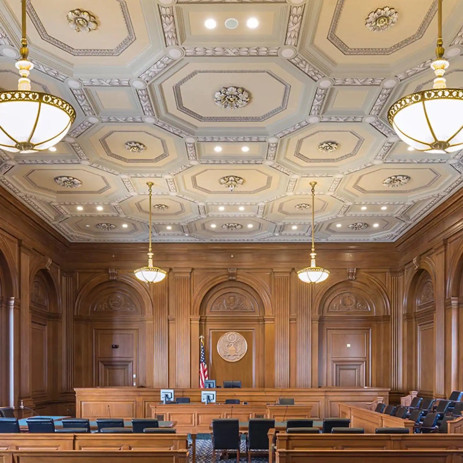 Ornate courtroom with rich wooden paneling and a decorative ceiling.