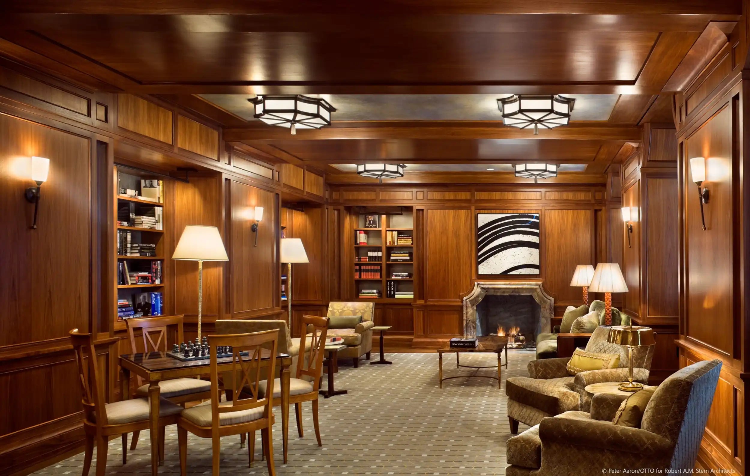 A richly paneled room with multiple seating areas and a fireplace.