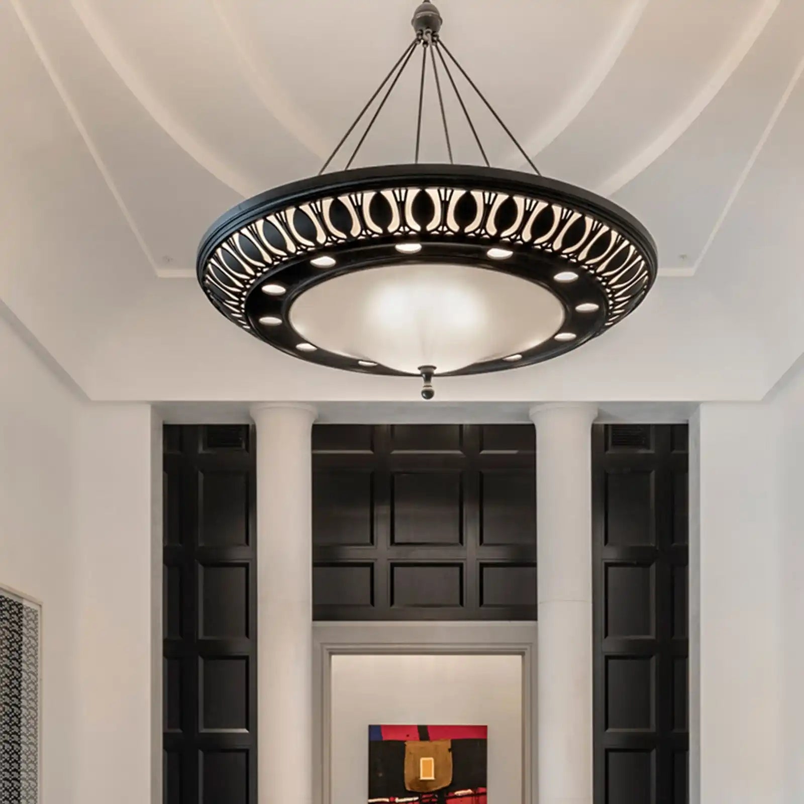 A round, black chandelier with a decorative, ornate border and a central, frosted glass dome.