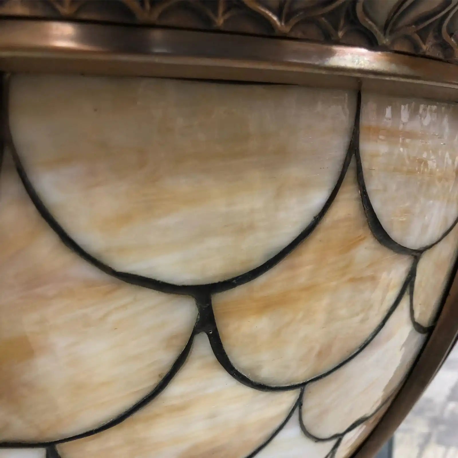Stained glass lamp shade with scallop-shaped iridescent panels.