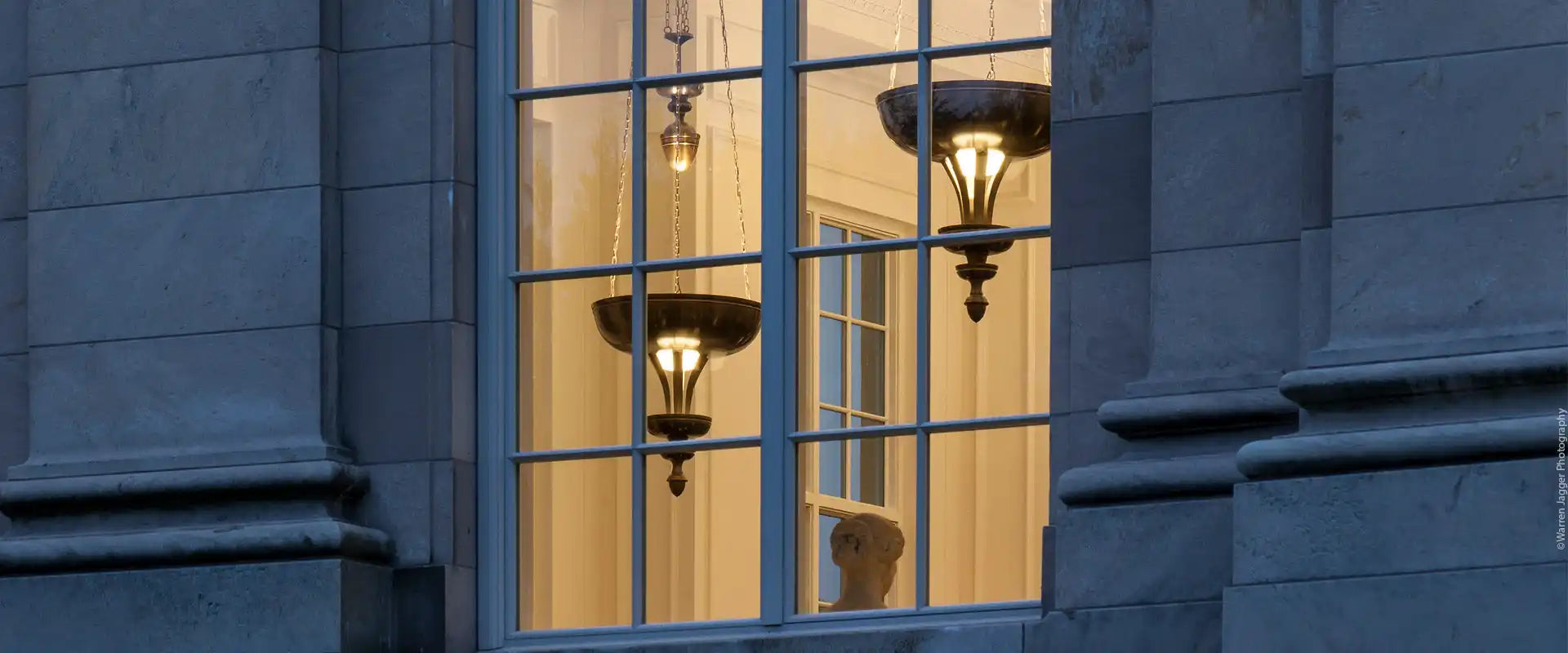 Window with illuminated ornate hanging light fixtures.