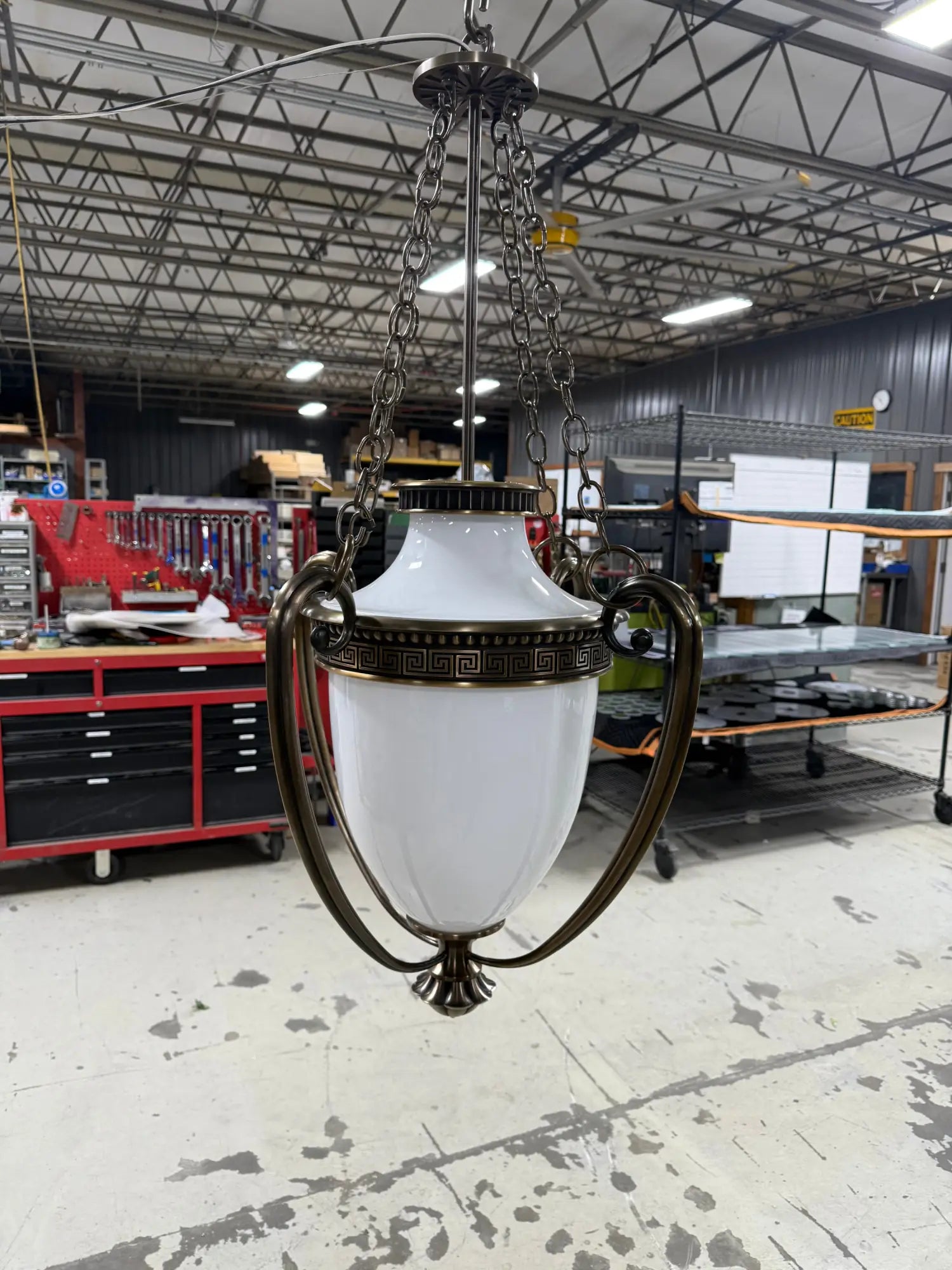 Ornate white glass pendant light with bronze accents and chain suspension for historic courthouse