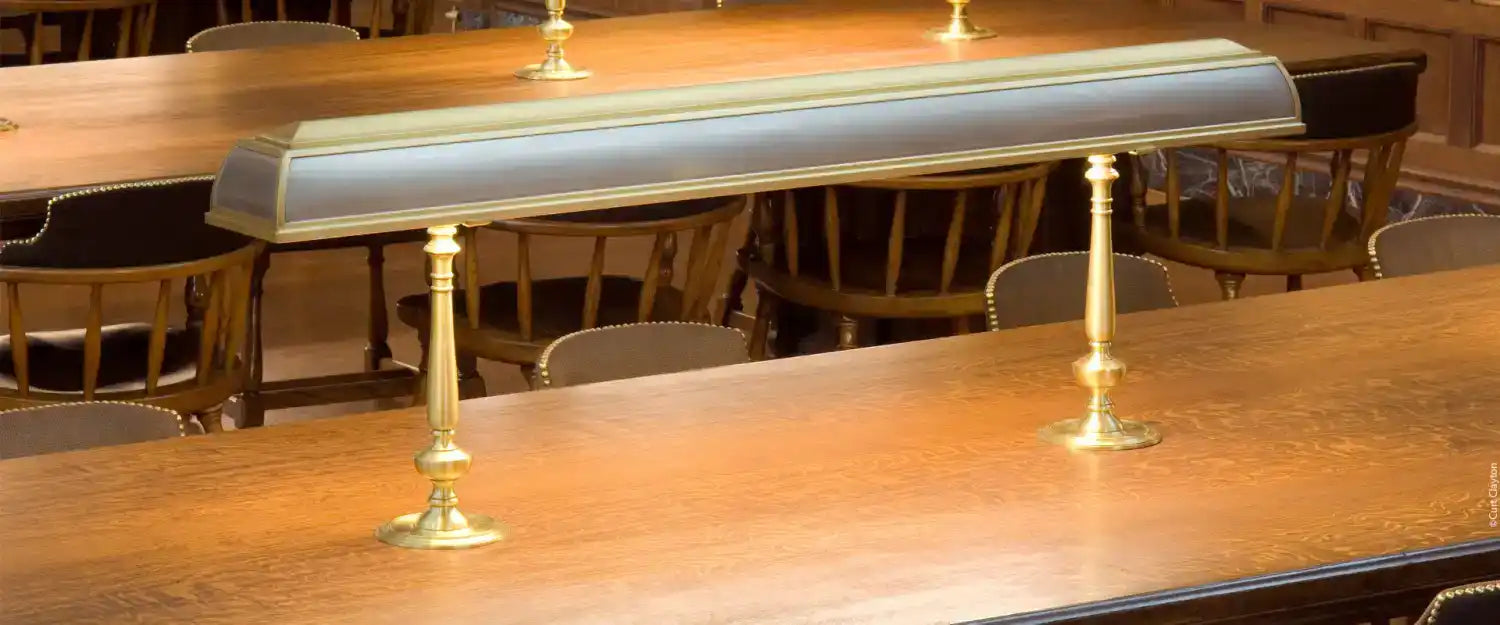 A brass library lamp with a dark, rectangular shade.