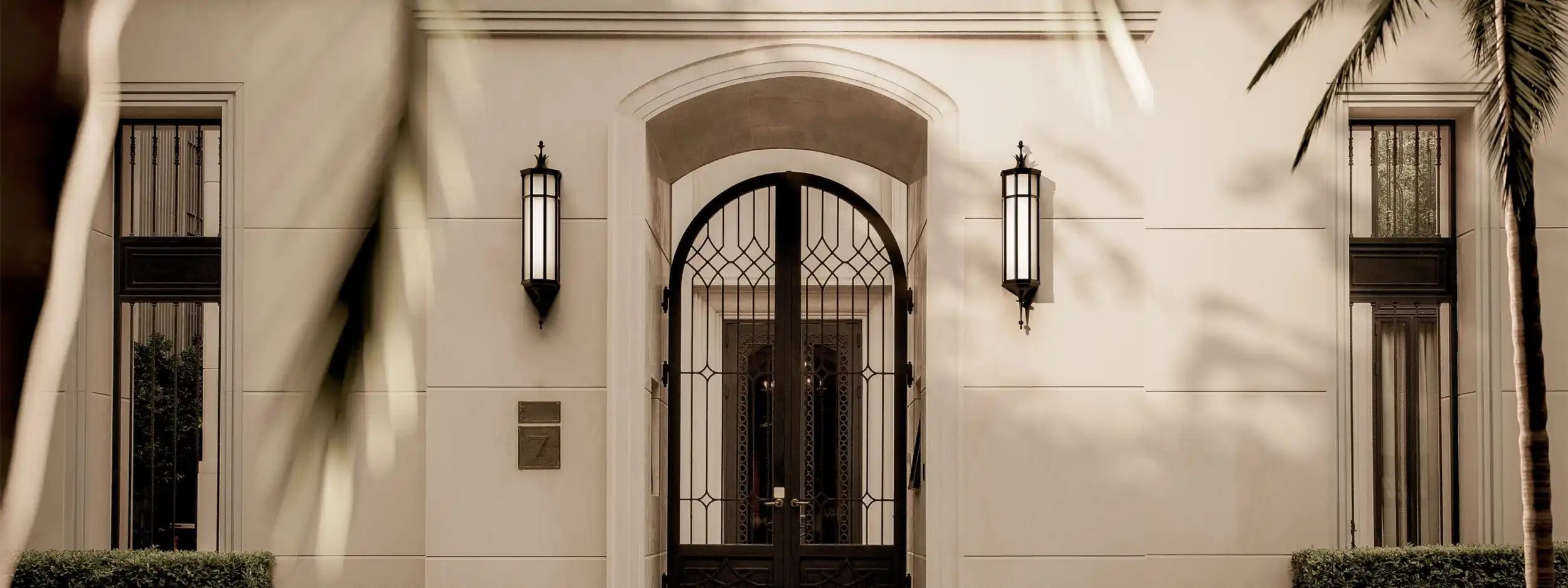 Elegant building facade with an arched entrance and ornate ironwork doors.