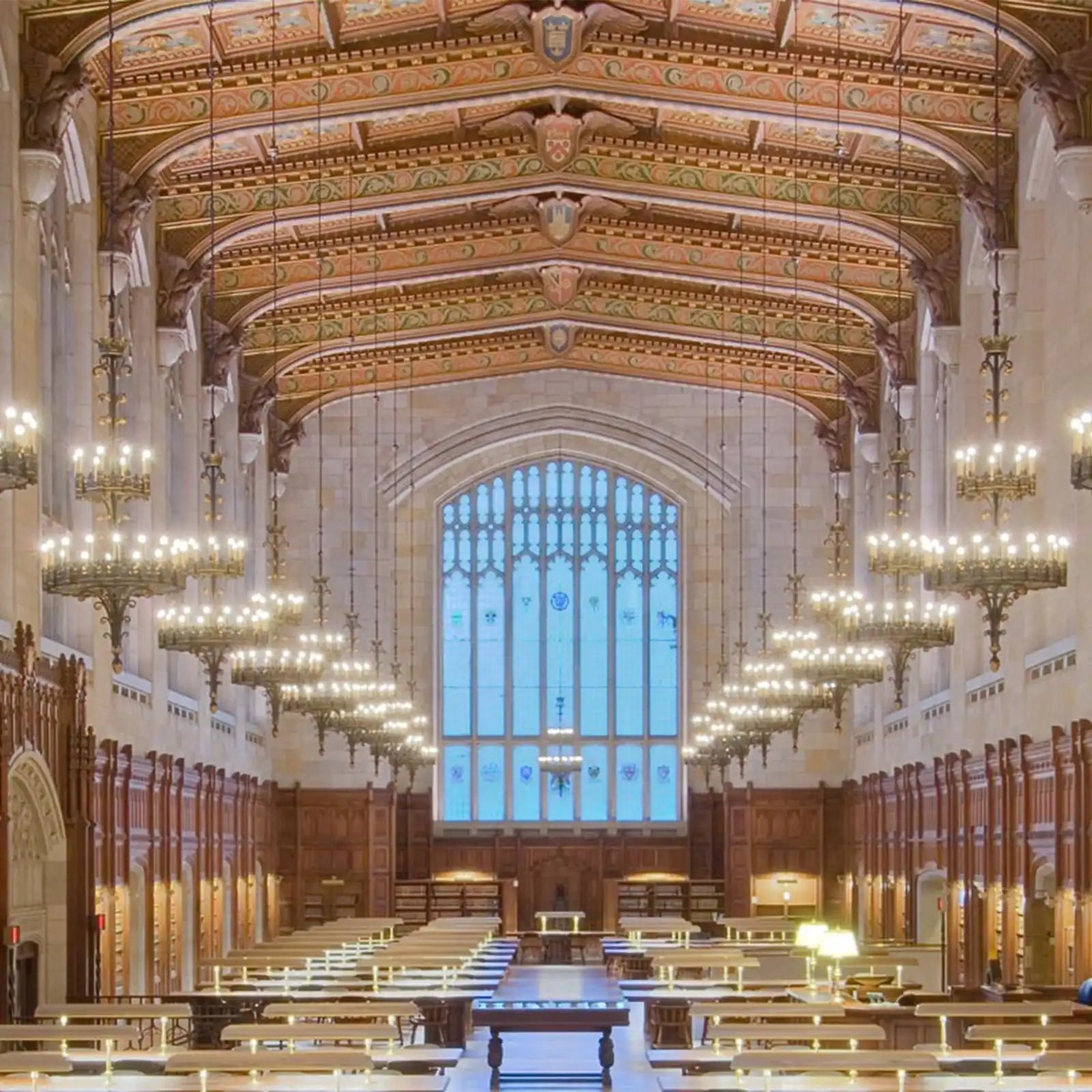 A grand, ornate reading room with multiple chandeliers and a large stained-glass window.