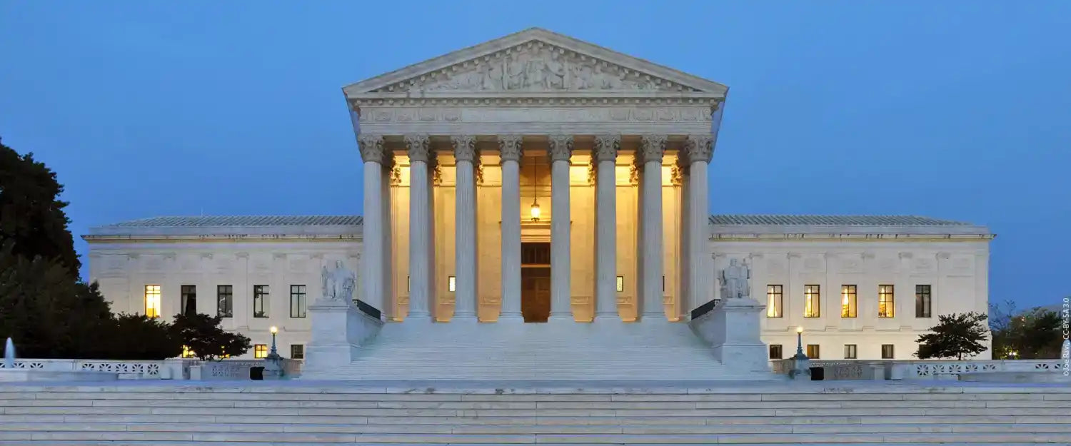 Neoclassical marble building with a grand entrance and illuminated windows.