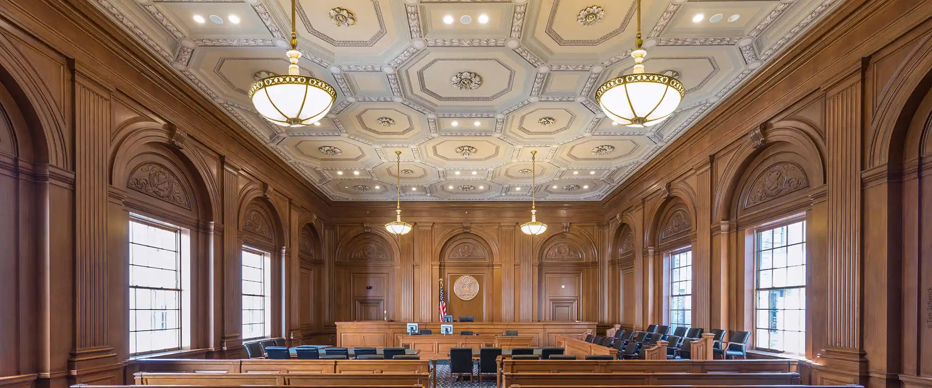 An ornate courtroom with rich wood paneling and a decorative ceiling.